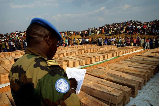 A UN peacekeeper documents rows of coffins at the Gatumba funeral